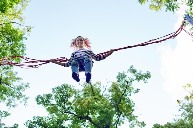 Outdoor actieve recreatie en pretpark, tienermeisje met plezier springen op trampoline met elastische touwen