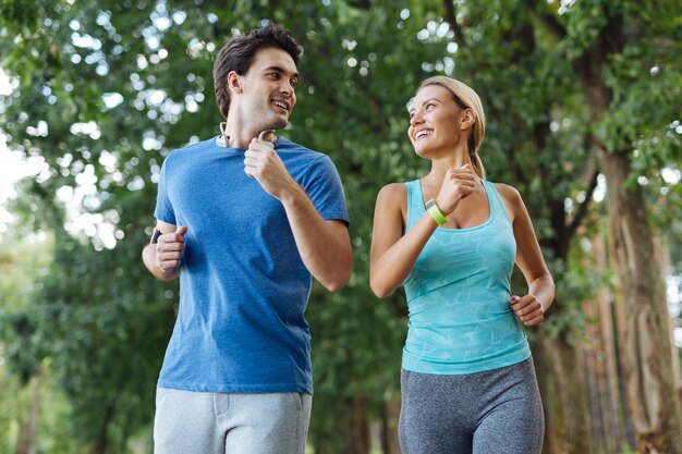 Attività all'aperto. belle coppie sane che sorridono mentre fanno jogging insieme nel bosco