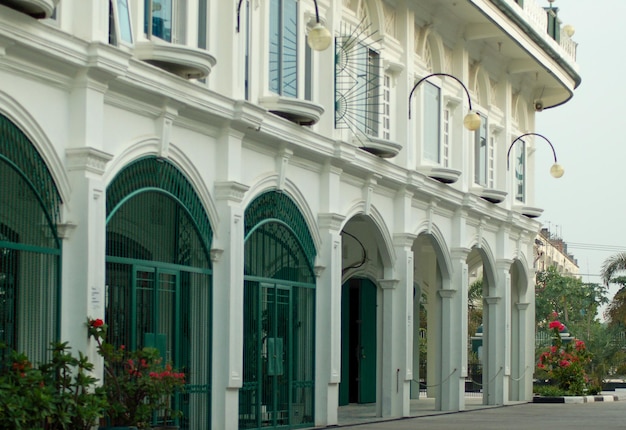 Photo the outdoor architecture of a white avantgarde style building is equipped with a green iron fence