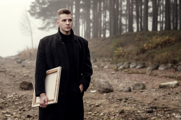 outdoor artist on the beach near the sea and forest, young male artist walks in autumn near the sea