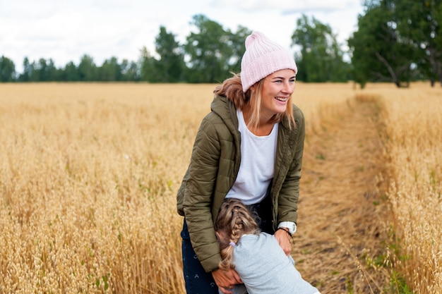 Outdoor atmospheric lifestyle photo of young beautiful  darkhaired woman mother with baby   in knitting hat in sunny autumn day