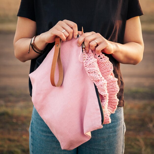 Foto foto di uno stile di vita atmosferico all'aperto di una giovane bella donna dai capelli scuri che sorride e lavora a maglia con un uncinetto a maglia da un filo di lana naturale un sudore rosa