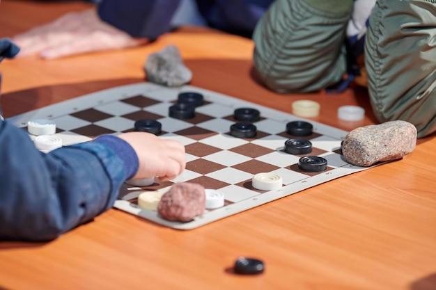 Outdoor checkers tournament on paper checkerboard on table close up players hands