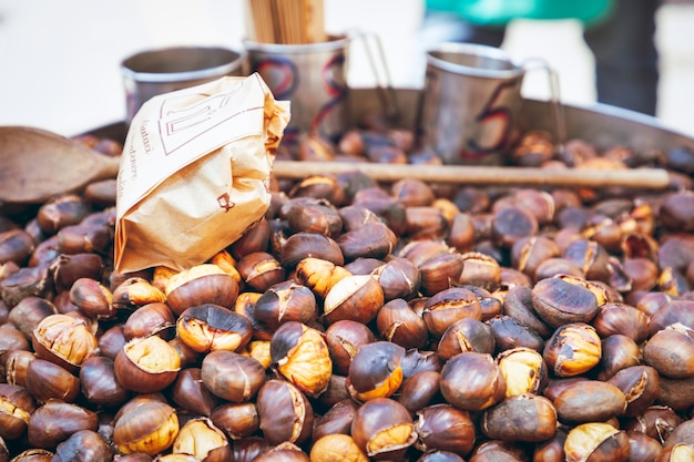 Outdoor chestnut roaster with chestnuts measuring cups and wooden spoon Selective focus