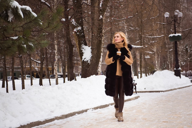 Outdoor close up photo of young beautiful happy smiling girl walking on street in winter