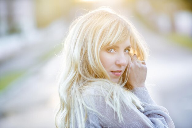 Outdoor close up portrait beautiful blonde girl with youth and skin care attractive looking at camera