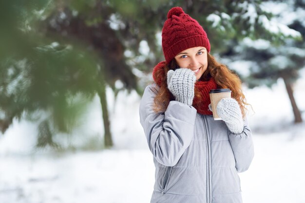 Outdoor close up portrait of young beautiful girl with hot cup of coffe. Winter holidays concept.