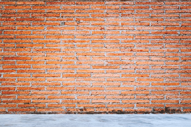 Outdoor concrete floor texture with red bricks wall background.