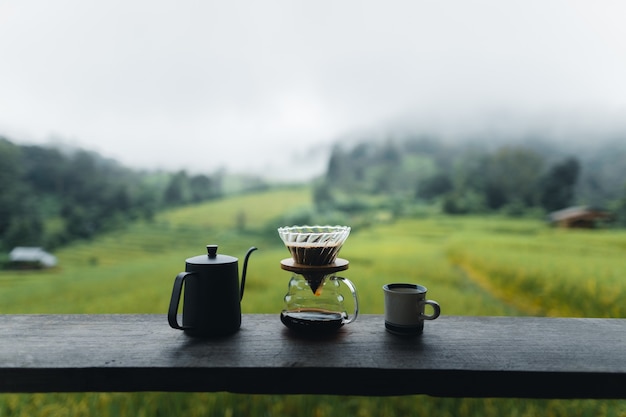 Outdoor drip coffee maker on wooden table rice field background