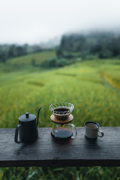 Outdoor drip coffee maker on wooden table rice field background