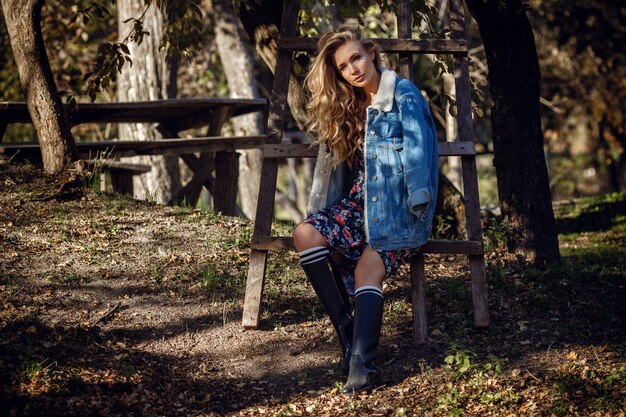 Outdoor fall portrait of girl with hat and jeans wear. Nature background, rural landscape, country style near a lake in the forest