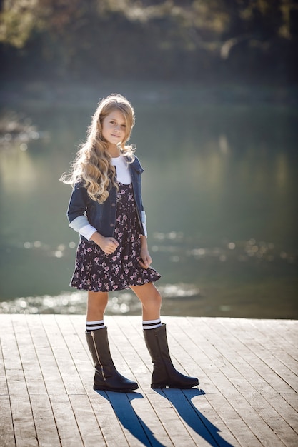 Outdoor fall portrait of girl with hat and jeans wear. Nature background, rural landscape, country style near a lake in the forest