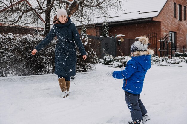 幸せな冬の休日のための屋外の家族の活動幸せな母と2人の息子が雪玉を遊んでいます