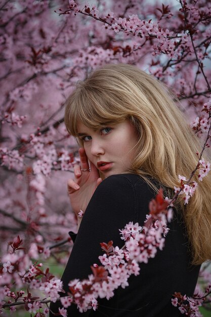 Outdoor fashion foto van een mooie jonge dame in een roze kersenbloesemtuin. als een sakura in Japan.