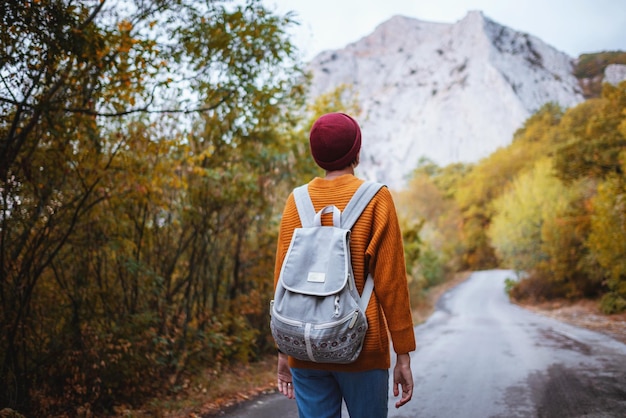 Outdoor fashion photo of young beautiful lady surrounded autumn forest in mountains