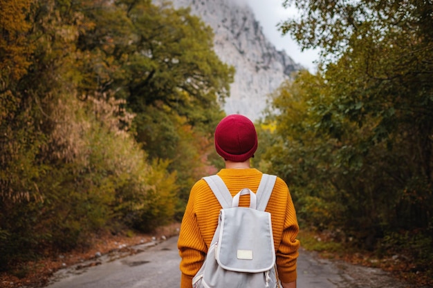 Outdoor fashion photo of young beautiful lady surrounded autumn forest in mountains