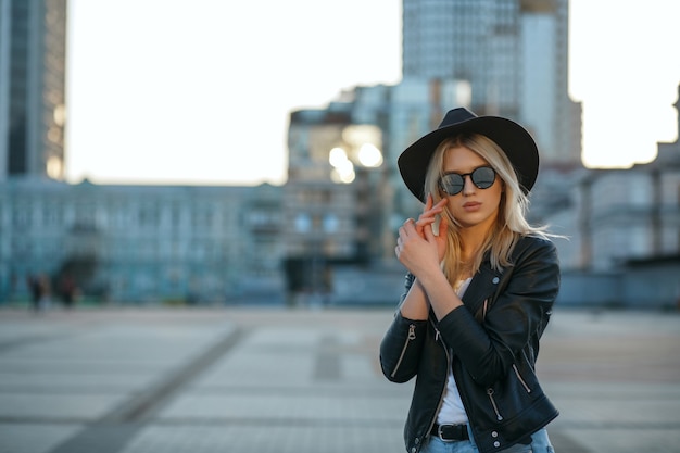 Outdoor fashion portrait of a gorgeous blonde woman wearing hat and mirror glasses. Space for text