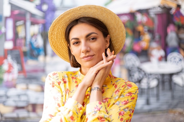 Outdoor fashion portrait of woman in yellow summer dress on street colourful wall