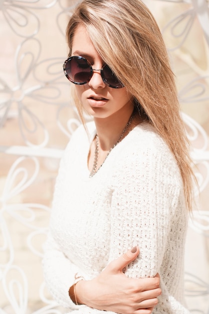 Outdoor fashion portrait of young pretty woman with round sunglasses