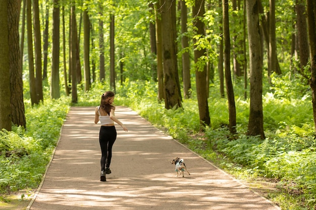 ペットとの屋外ゲーム女の子は楽しんでいる犬と一緒に走る