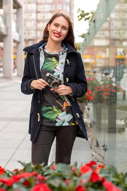 Outdoor herfst glimlachend levensstijl portret van mooie jonge vrouw, plezier in de stad met camera, reisfoto van fotograaf. Foto's maken in hipsterstijl.