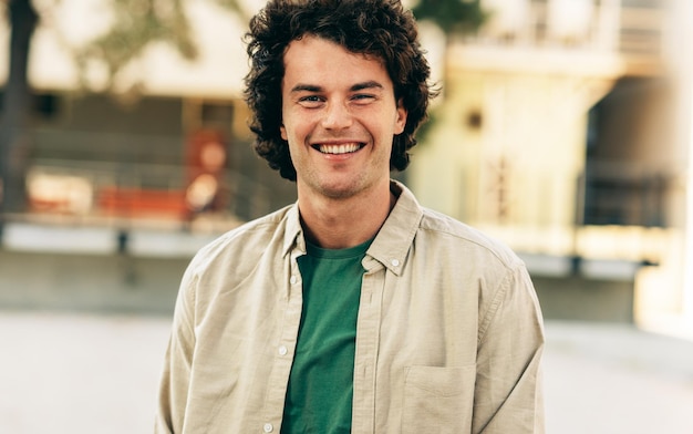 Outdoor horizontal portrait of happy handsome young man smiling and posing for advertisement looking at the camera standing at city street Happy smart student male posing outside People emotion