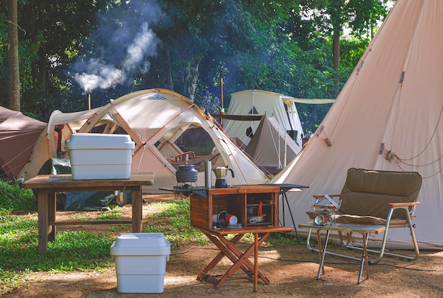 Outdoor kitchen equipment on wooden table with field tents\
group in camping area at natural park