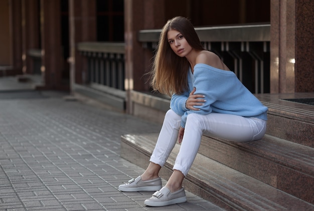 Outdoor lifestyle fashion portrait of pretty young girl on urban scene