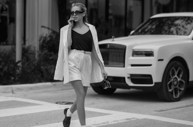 Photo outdoor lifestyle portrait of pretty young fashion model in urban background outdoor elegant fashionable woman walking in street summer lifestyle portrait of stylish girl wearing trendy outfit