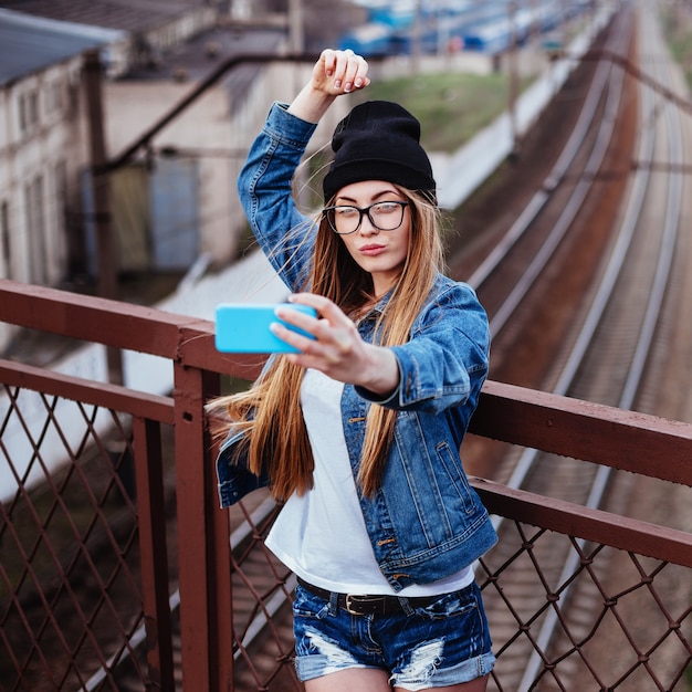 Outdoor lifestyle portrait of pretty young girl, wearing in hipster swag grunge style on urban background