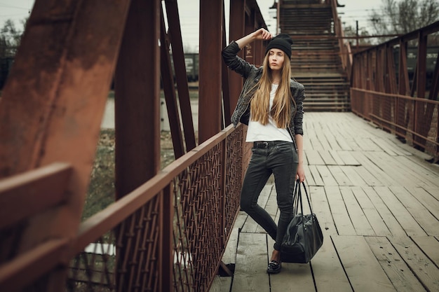 Outdoor lifestyle portrait of pretty young girl wearing in hipster swag grunge style on urban background