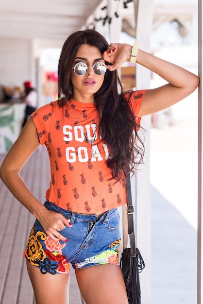 Outdoor lifestyle portrait of young amazing brunette woman orange print tshirt