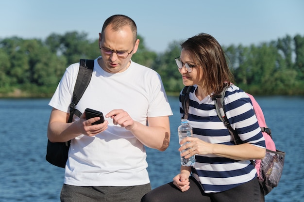 Outdoor mature couple using smartphone