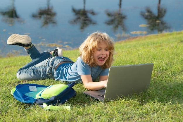 Outdoor online onderwijs met laptop kind liggend op het gras met behulp van laptop notebook concept van outdoor edu