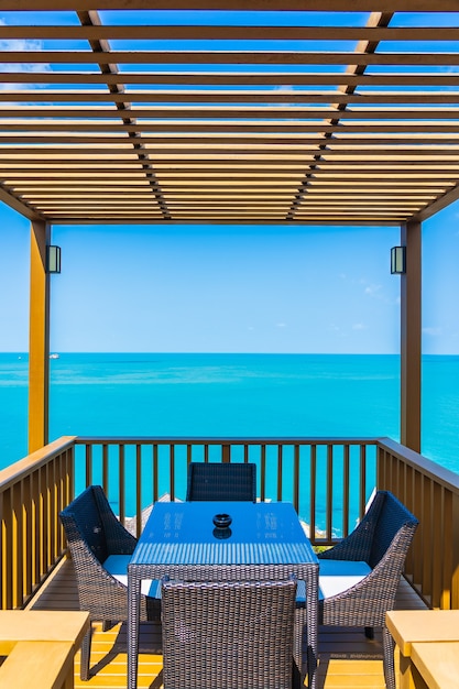 Outdoor patio with empty chair and table with sea ocean with white cloud blue sky view