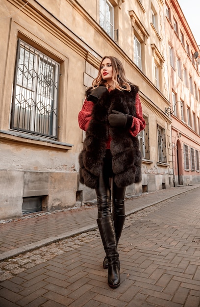 Outdoor photo of fashionable female model walking around city in winter vacation.