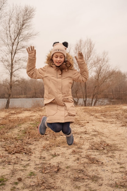 Outdoor portrait of adorable 10- 11 year old girl wearing warm jacket. A schoolgirl in a beige hat.