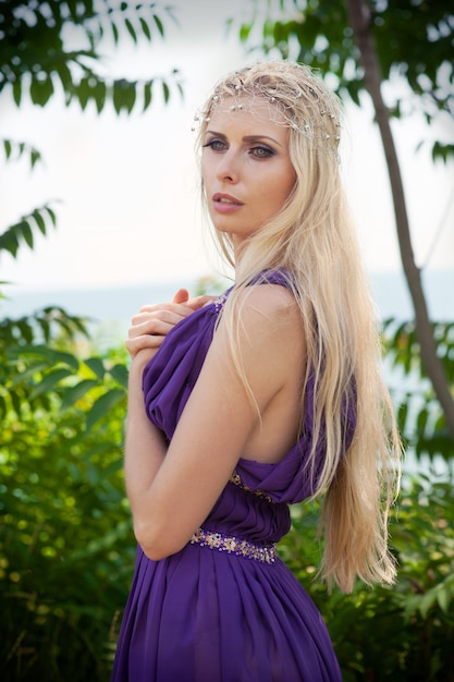 Outdoor portrait of beautiful blond woman in purple dress