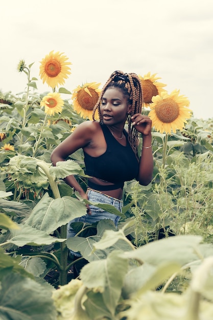 Outdoor portrait of beautiful happy mixed race African American woman in a field of yellow flowers at sunset golden evening sunshine