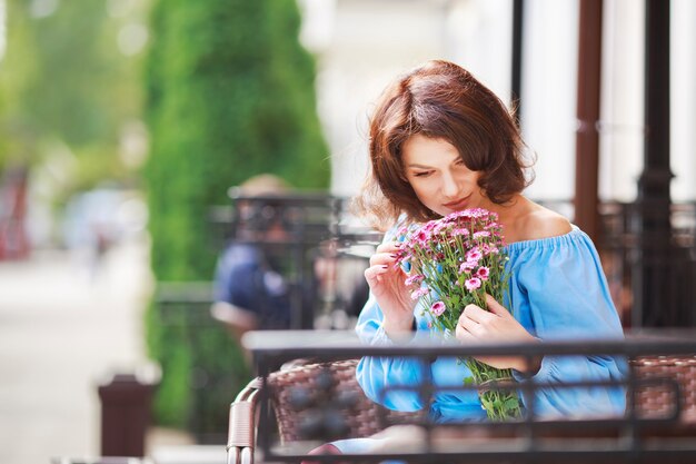 Outdoor portrait of beautiful woman at the table in a street city cafe.