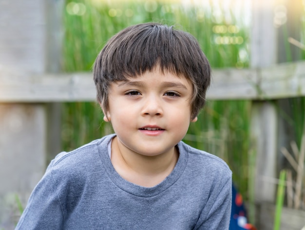 Outdoor portrait cute boy looking at camera with smiling face.