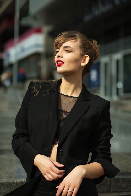 Outdoor portrait of fashionable brunette woman wears black suit walking at the avenue