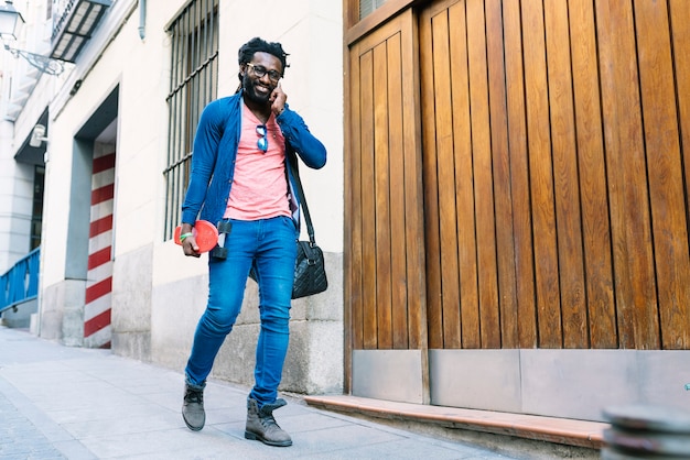 outdoor portrait of handsome african young man using mobile in the street.