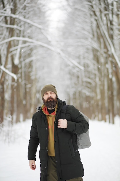 Outdoor portrait of handsome man in coat and scurf. Bearded man in the winter woods.