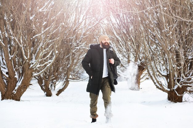 Outdoor portrait of handsome man in coat and scurf. Bearded man in the winter woods.