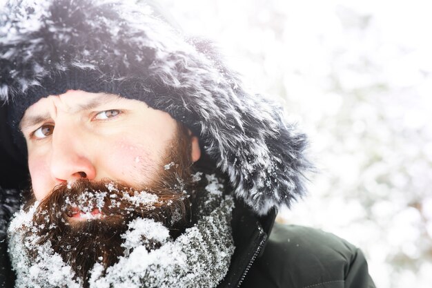 Ritratto all'aperto dell'uomo bello in cappotto e forfora. uomo barbuto nei boschi invernali.