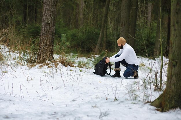 Outdoor portrait of handsome man in coat and scurf. Bearded man in the winter woods.