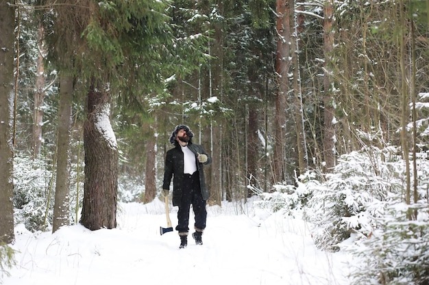 Ritratto all'aperto di bell'uomo in cappotto e scurf. uomo barbuto nei boschi d'inverno.