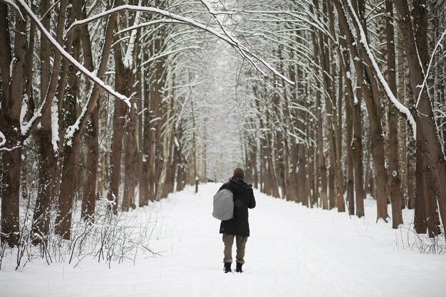 Outdoor portrait of handsome man in coat and scurf. Bearded man in the winter woods.