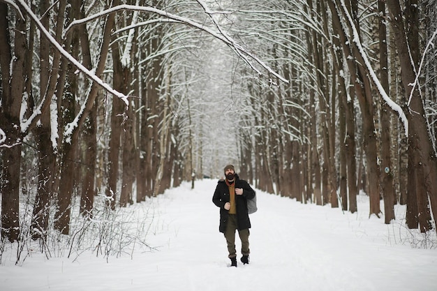 Outdoor portrait of handsome man in coat and scurf. Bearded man in the winter woods.